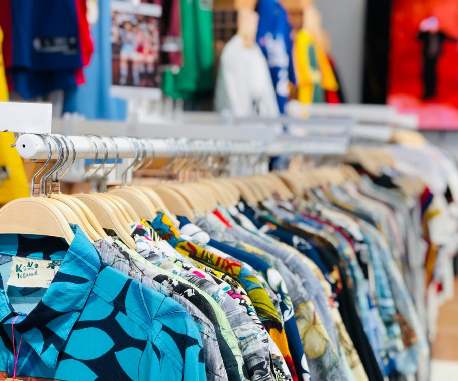 A vibrant collection of Hawaiian shirts on hangers in a clothing store with varied designs and colors.